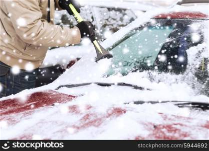 transportation, winter, weather, people and vehicle concept - closeup of man cleaning snow from car windshield with brush