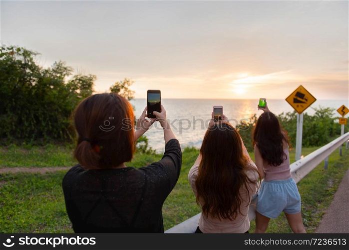 Travel and freedom,Asian women take a picture against a background of sunset and sea coast.The adventures and directions for travel .