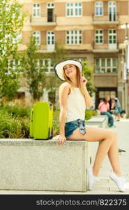Travel and journey. Female tourist traveller. Girl with green luggage suitcase baggage travelling visiting.. Woman tourist with suitcase on street