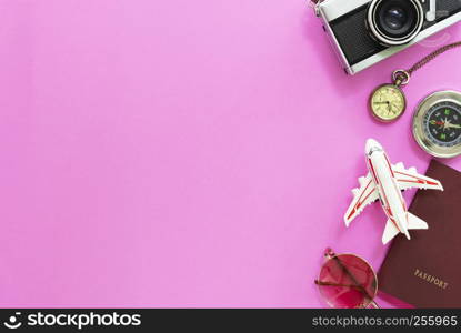 Travel and summer times concept. Flat lay of accessories, passport, sunglasses, compass, watch, airplane model and camera on pink background.