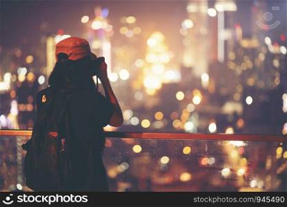 Travel and technology. Young woman taking photo with her smartphone of Petronas Twins Towers in Kuala-Lumpur at evening
