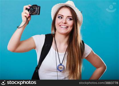 Travel and tourism active lifestyle concept. Tourist woman with backpack taking photo with camera on blue