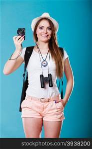Travel and tourism active lifestyle concept. Tourist woman with backpack taking photo with camera on blue