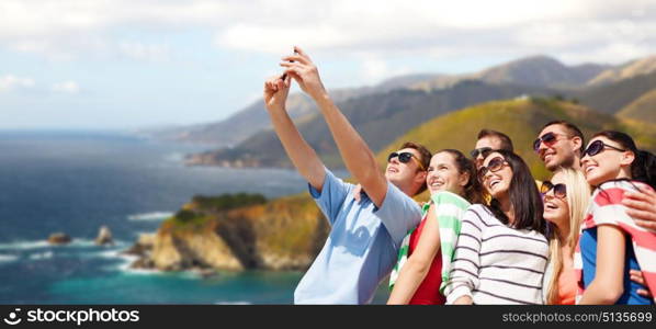 travel and tourism concept - group of happy friends taking selfie by cell phone over big sur coast of california background. group of happy friends taking selfie by cell phone. group of happy friends taking selfie by cell phone