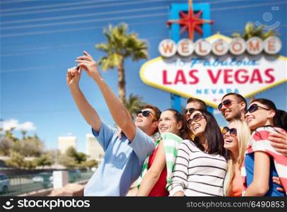 travel and tourism concept - group of happy friends taking selfie by cell phone over welcome to fabulous las vegas sign background. group of happy friends taking selfie by cell phone. group of happy friends taking selfie by cell phone