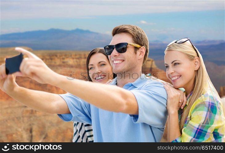 travel and tourism concept - group of happy friends taking selfie by cell phone over grand canyon national park background. group of happy friends taking selfie by cell phone. group of happy friends taking selfie by cell phone