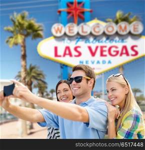travel and tourism concept - group of happy friends taking selfie by cell phone over welcome to fabulous las vegas sign background. group of happy friends taking selfie by cell phone. group of happy friends taking selfie by cell phone