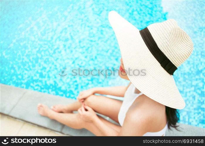 travel and vacation concept - close up of young woman relaxing at a pool in summer, selective focus