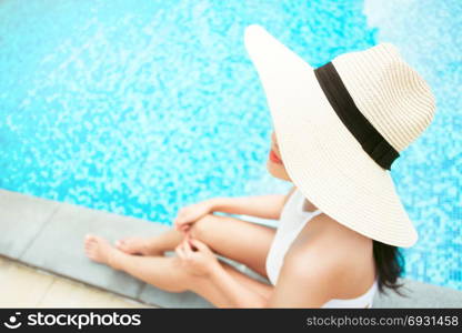travel and vacation concept - close up of young woman relaxing at a pool in summer, selective focus
