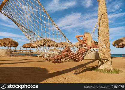 Travel and vacation concept - Woman relaxing on hammock on the beach.. Travel and vacation concept - Woman relaxing on hammock on the beach