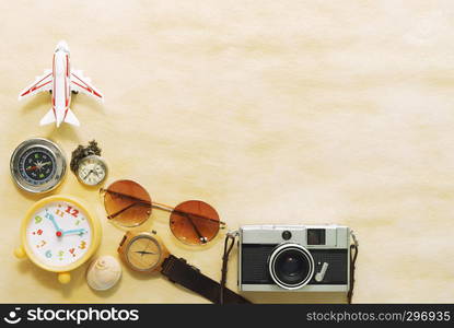 Travel background concept. Camera, sunglasses, compass and airplane model on wood table with free space for text.