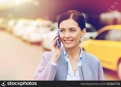 travel, business trip, people and tourism concept - smiling young woman calling and talking on smartphone over taxi station or city street. smiling woman with smartphone over taxi in city. smiling woman with smartphone over taxi in city