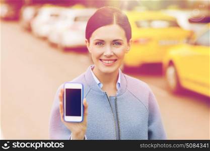 travel, business trip, people and tourism concept - smiling young woman showing smartphone blank screen over taxi station or city street. smiling woman showing smartphone over taxi in city. smiling woman showing smartphone over taxi in city