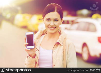 travel, business trip, people and tourism concept - smiling young woman showing smartphone blank screen over taxi station or city street. smiling woman showing smartphone over taxi in city