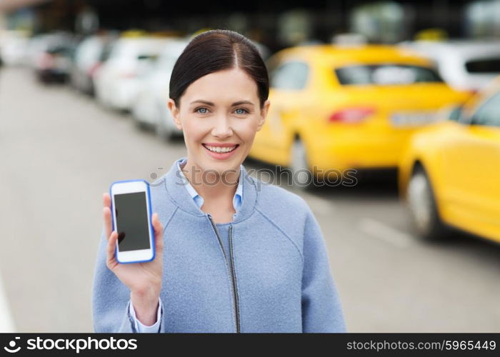 travel, business trip, people and tourism concept - smiling young woman showing smartphone blank screen over taxi station or city street