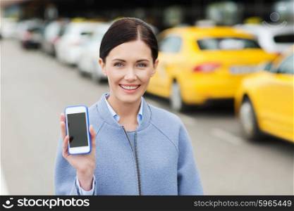 travel, business trip, people and tourism concept - smiling young woman showing smartphone blank screen over taxi station or city street