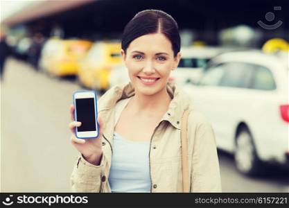 travel, business trip, people and tourism concept - smiling young woman showing smartphone blank screen over taxi station or city street