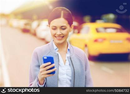 travel, business trip, people and tourism concept - smiling young woman with smartphone over taxi station or city street. smiling woman with smartphone over taxi in city. smiling woman with smartphone over taxi in city