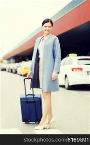 travel, business trip, people and tourism concept - smiling young woman with travel bag over taxi at airport terminal or railway station