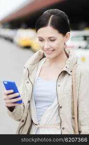 travel, business trip, people and tourism concept - smiling young woman with smartphone over taxi station or city street