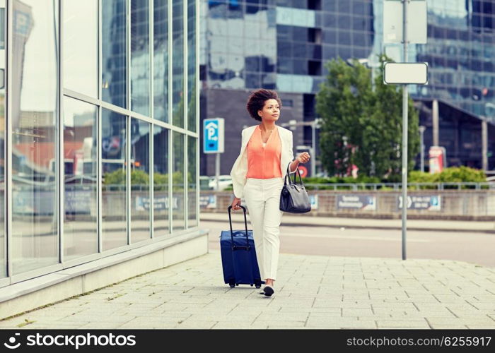 travel, business trip, people and tourism concept - young african american woman with travel bag walking down city street