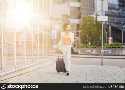 travel, business trip, people and tourism concept - young african american woman with travel bag walking down city street