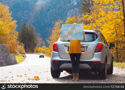 travel by car. Road trip - tourist girl with a map is standing near the car. Austria. roadtrip