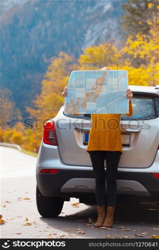 travel by car. Road trip - tourist girl with a map is standing near the car. Austria
