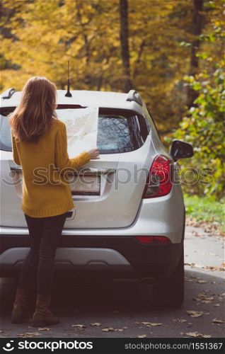 travel by car. Road trip - tourist girl with a map is standing near the car. Austria. active lifestyle