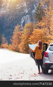 travel by car. Road trip - tourist girl with a map is standing near the car. Austria