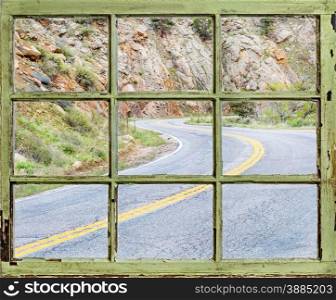 travel concept - a view of windy mountain road through vintage, grunge, sash window with dirty glass