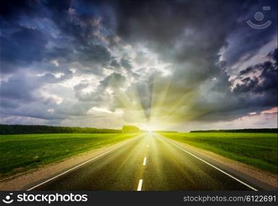 Travel concept background - road and stormy dramatic sky on sunset. Road and stormy sky on sunset