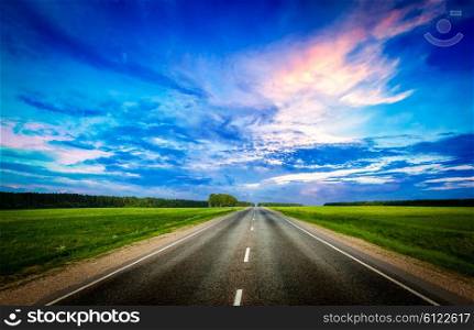 Travel concept background - road and stormy dramatic sky on sunset. Road and stormy sky