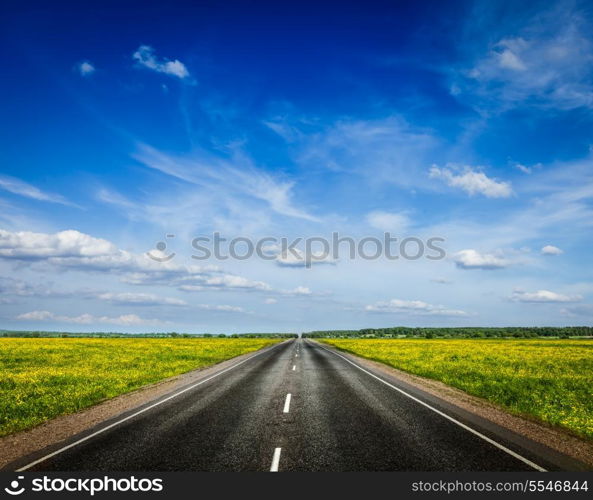 Travel concept background - road in blooming spring meadow