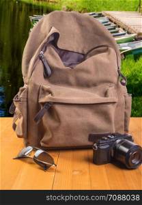 Travel concept. Backpack, camera and glasses on a wooden background. Backpack, camera and sunglasses on a wooden table
