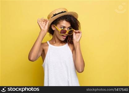 Travel concept - Close up Portrait young beautiful attractive African American woman with trendy hat and sunglass smiling. Yellow Pastel studio Background. Copy space. Travel concept - Close up Portrait young beautiful attractive African American woman with trendy hat and sunglass smiling. Yellow Pastel studio Background. Copy space.