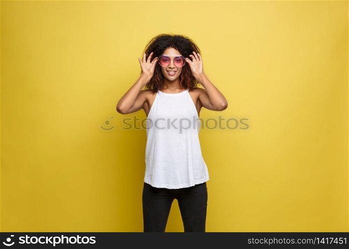 Travel concept - Close up Portrait young beautiful attractive African American woman with trendy sunglass smiling. Yellow Pastel studio Background. Copy space. Travel concept - Close up Portrait young beautiful attractive African American woman with trendy sunglass smiling. Yellow Pastel studio Background. Copy space.