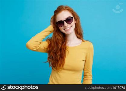 Travel concept - Close up Portrait young beautiful attractive ginger red hair girl with trendy sunglass smiling. Blue Pastel Background. Copy space.