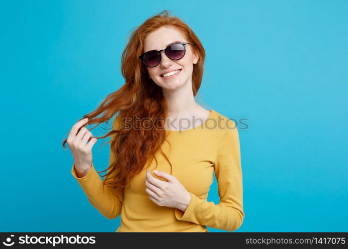 Travel concept - Close up Portrait young beautiful attractive ginger red hair girl with trendy sunglass smiling. Blue Pastel Background. Copy space.