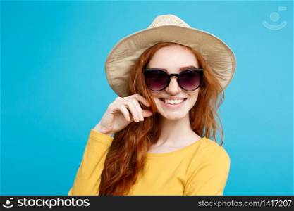 Travel concept - Close up Portrait young beautiful attractive ginger red hair girl with trendy hat and sunglass smiling. Blue Pastel Background. Copy space.