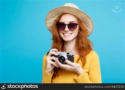 Travel concept - Close up Portrait young beautiful attractive redhair girl with trendy hat ,sunglass and vintage camera smiling to camera. Blue Pastel Background. Copy space.