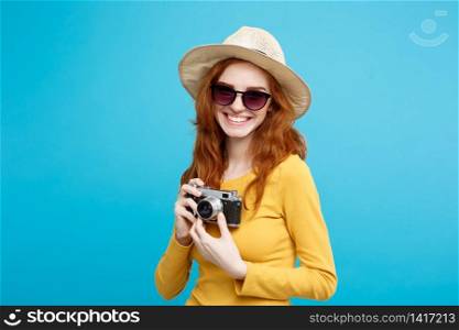 Travel concept - Close up Portrait young beautiful attractive redhair girl wtih trendy hat ,sunglass and vintage camera smiling to camera. Blue Pastel Background. Copy space.. Travel concept - Close up Portrait young beautiful attractive redhair girl with trendy hat ,sunglass and vintage camera smiling to camera. Blue Pastel Background. Copy space.