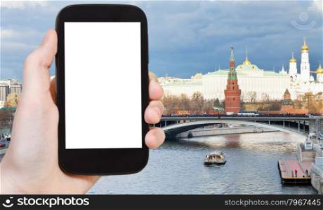 travel concept - hand holds smartphone with cut out screen and bridge and Moscow Kremlin on background