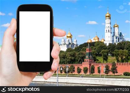 travel concept - hand holds smartphone with cut out screen and Cathedrals of Moscow Kremlin on background