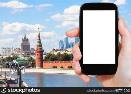 travel concept - hand holds smartphone with cut out screen and Moscow landmarks on background