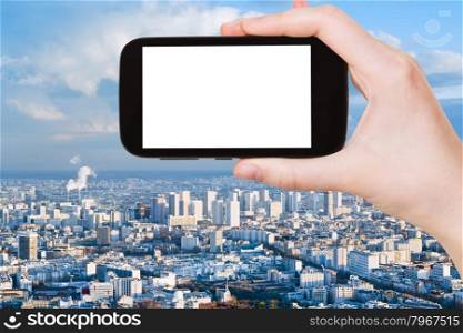travel concept - hand holds smartphone with cut out screen and Paris skyline on background