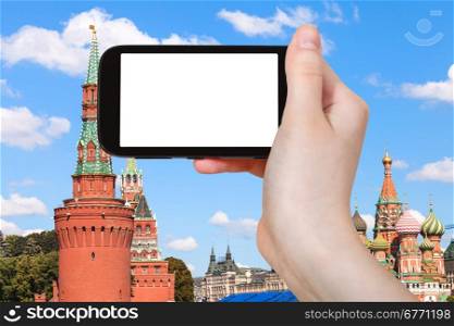 travel concept - hand holds smartphone with cut out screen and Red Towers of Moscow Kremlin on background