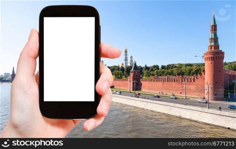 travel concept - hand holds smartphone with cut out screen and red walls of Moscow Kremlin on background