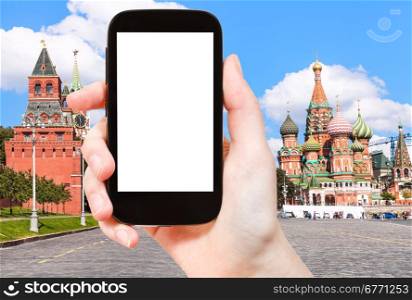travel concept - hand holds smartphone with cut out screen and Vasilevsky descent of Red Square with St Basil Cathedral on background
