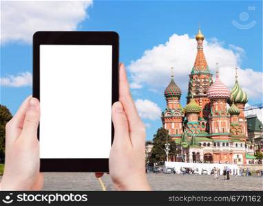 travel concept - hand holds tablet pc with cut out screen and Pokrovsky Cathedral on Red Square in Moscow on background
